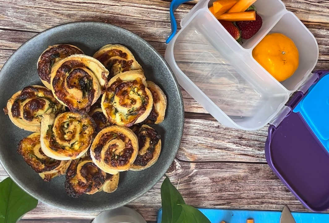 Gluten free pizza scrolls on a plate next to a lunch box